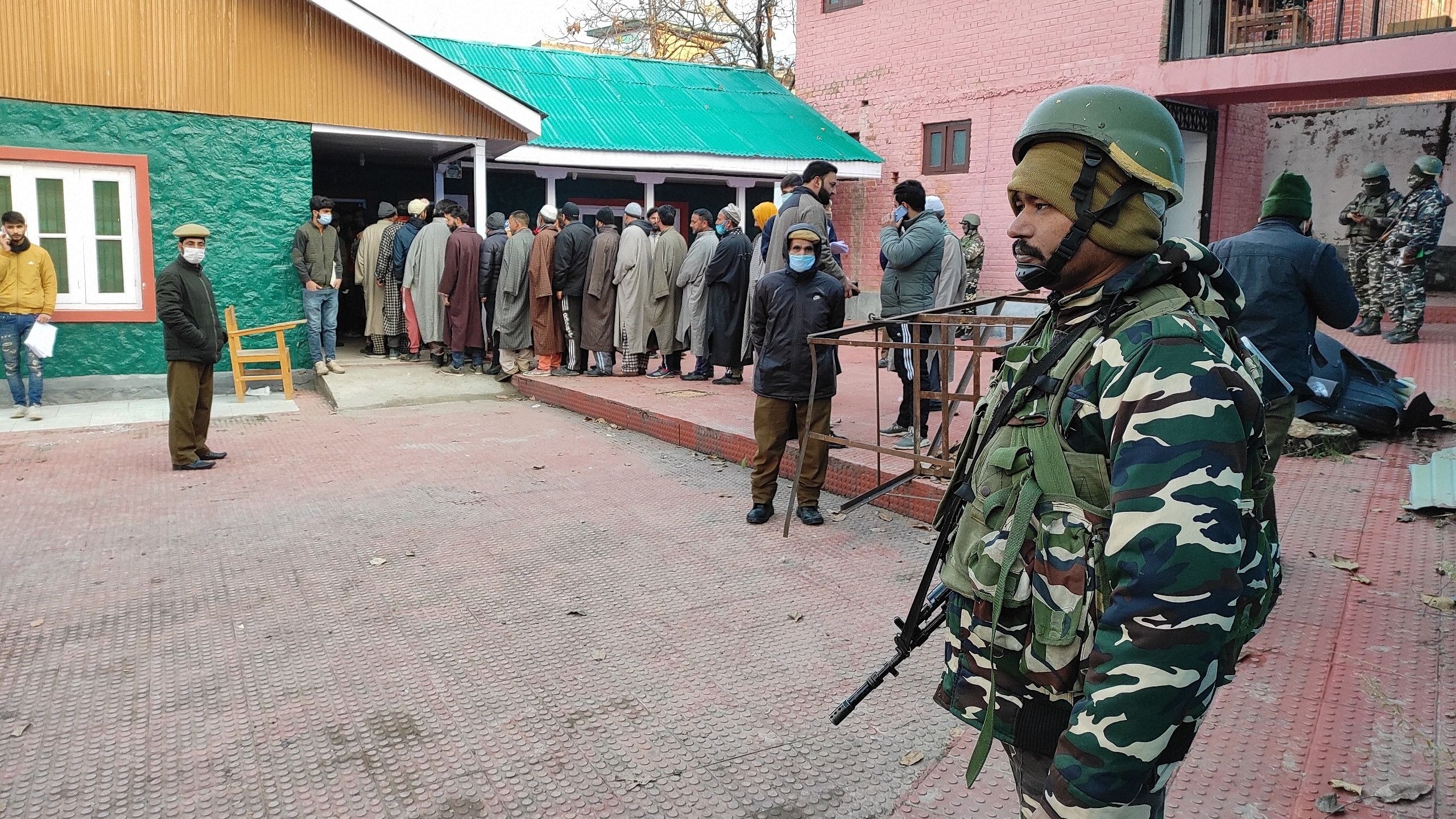 <div class="paragraphs"><p>A security official keeps a vigil as voters stand in a queue to cast their votes for the District Development Council election, at a polling station in Srinagar.</p></div>